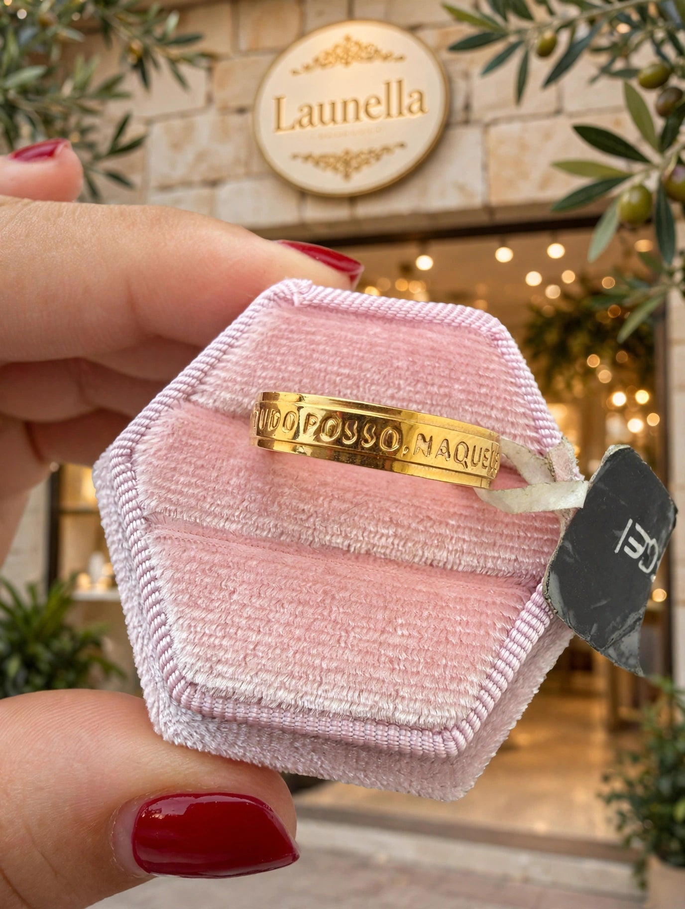 Anel Tudo Posso Naquele que Me Fortalece Rommanel - na caixa rosa hexagonal em frente à loja Launella com oliveira