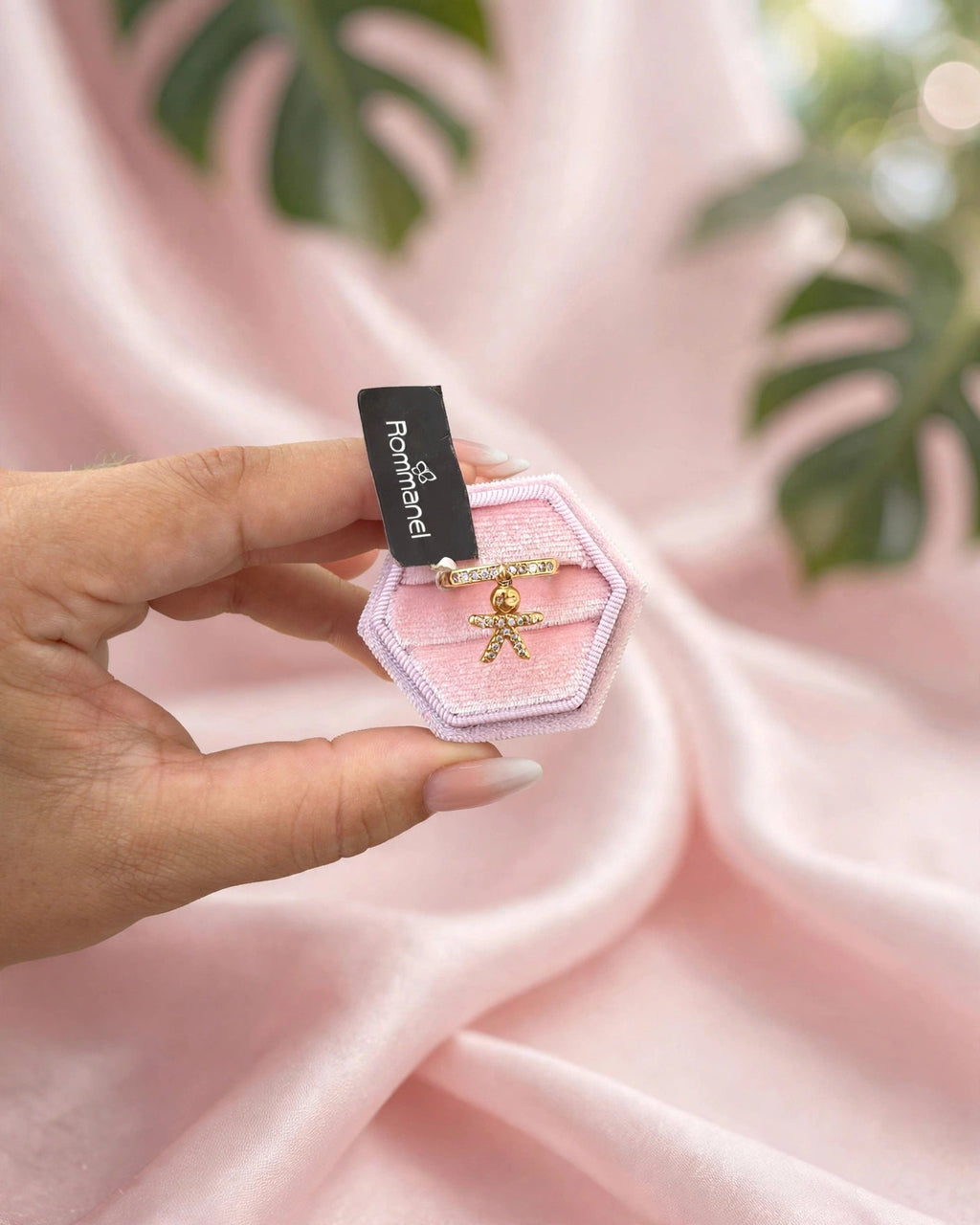 Anel Aparador Zircónias com Pingente Menino Rommanel - na caixa rosa hexagonal fundo cetim rosa com folha monstera