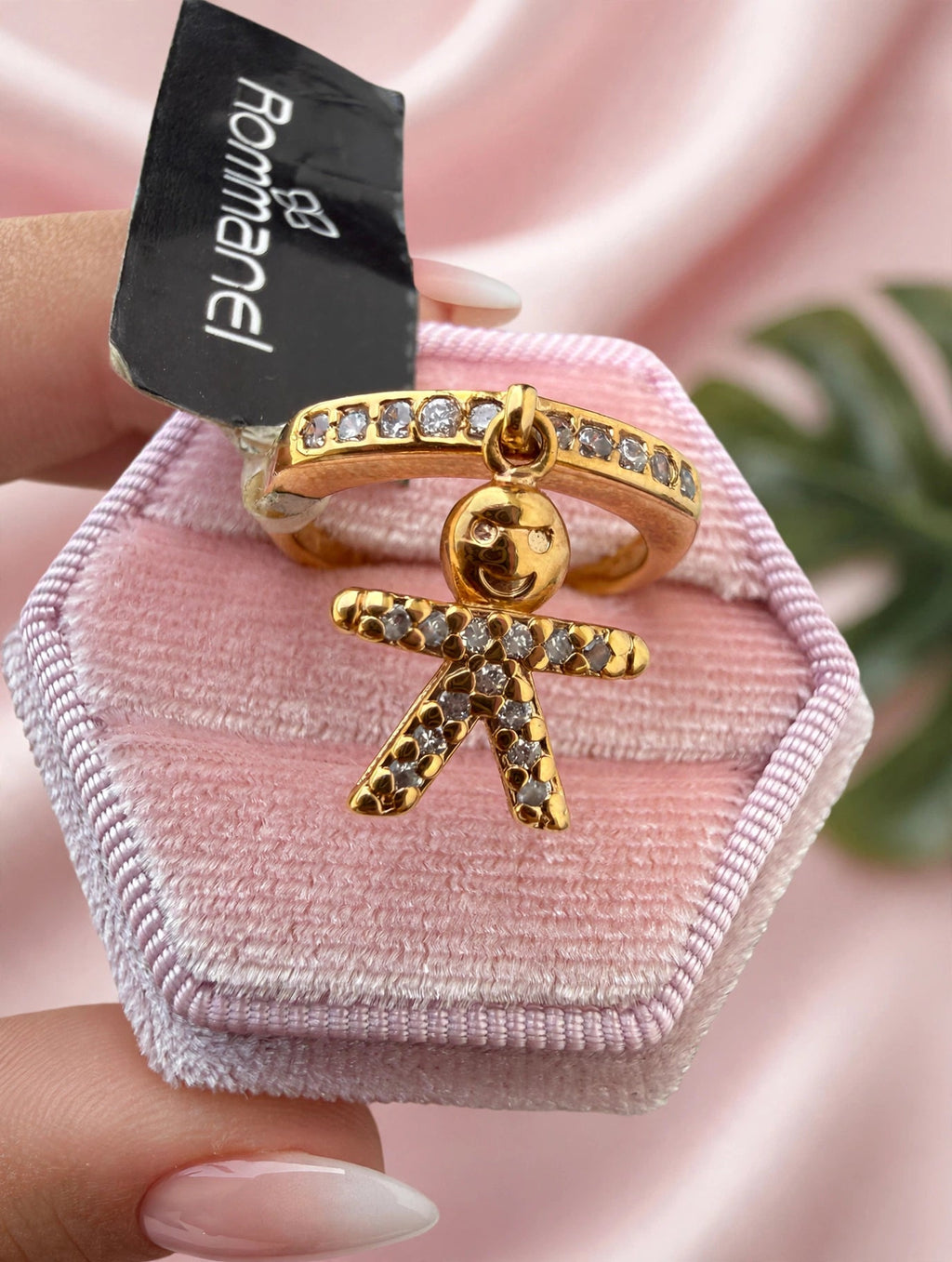 Anel Aparador Zircónias com Pingente Menino Rommanel - detalhe aproximado do pingente menino com zircónias fundo cetim rosa