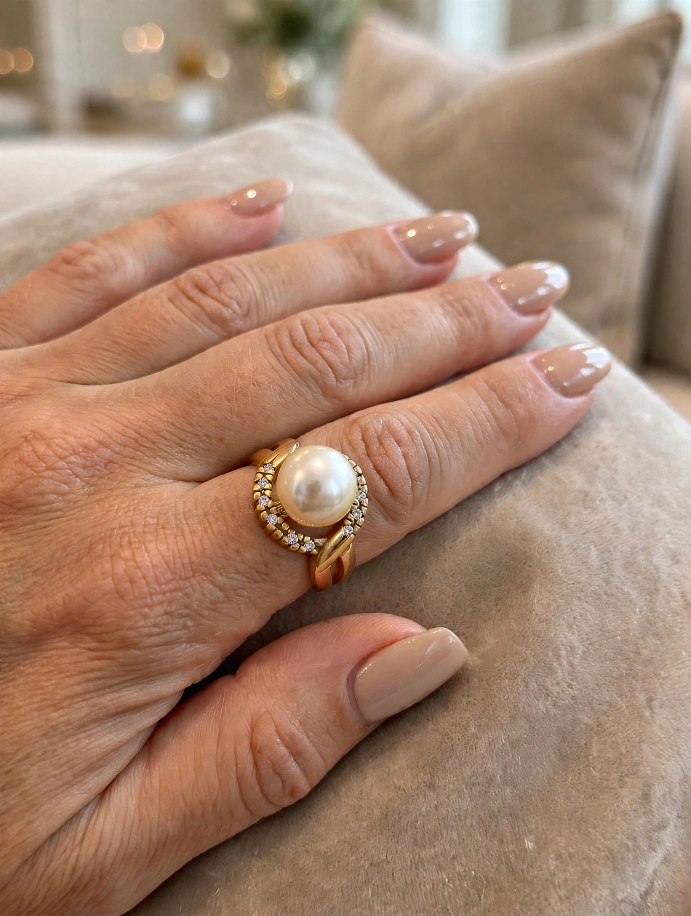 Anel Pérola com Halo de Zircónias Rommanel - no dedo com unhas nude sobre almofada bege interior