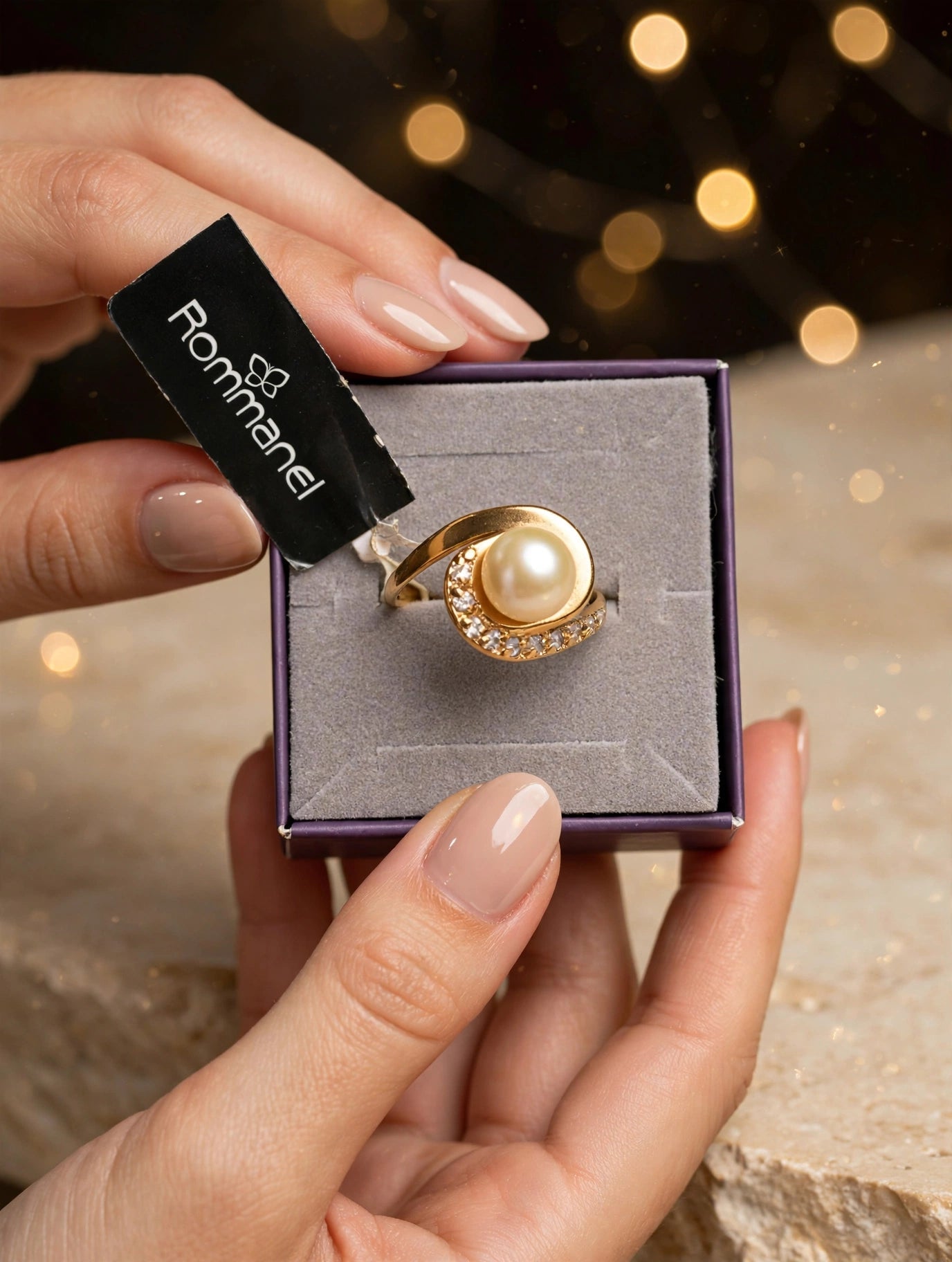 Anel Pérola Espiral Zircónias Rommanel - na caixa roxa veludo com etiqueta Rommanel preta fundo bokeh dourado