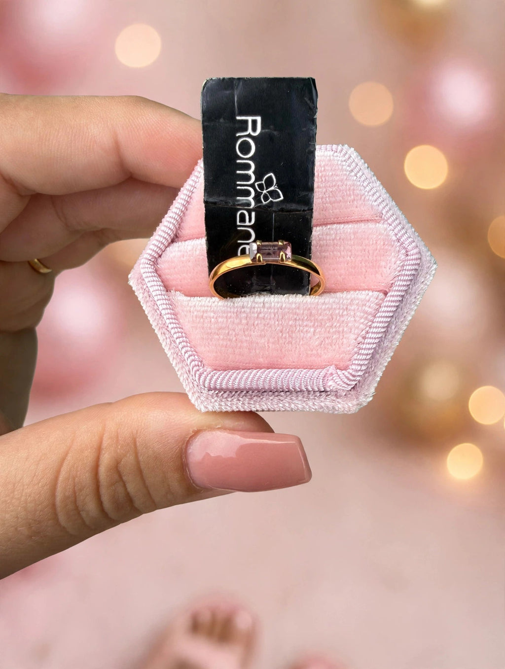 Anel Infantil Zircónia Roxa Baguette Rommanel - na caixa rosa hexagonal vista de cima fundo bokeh rosa e dourado